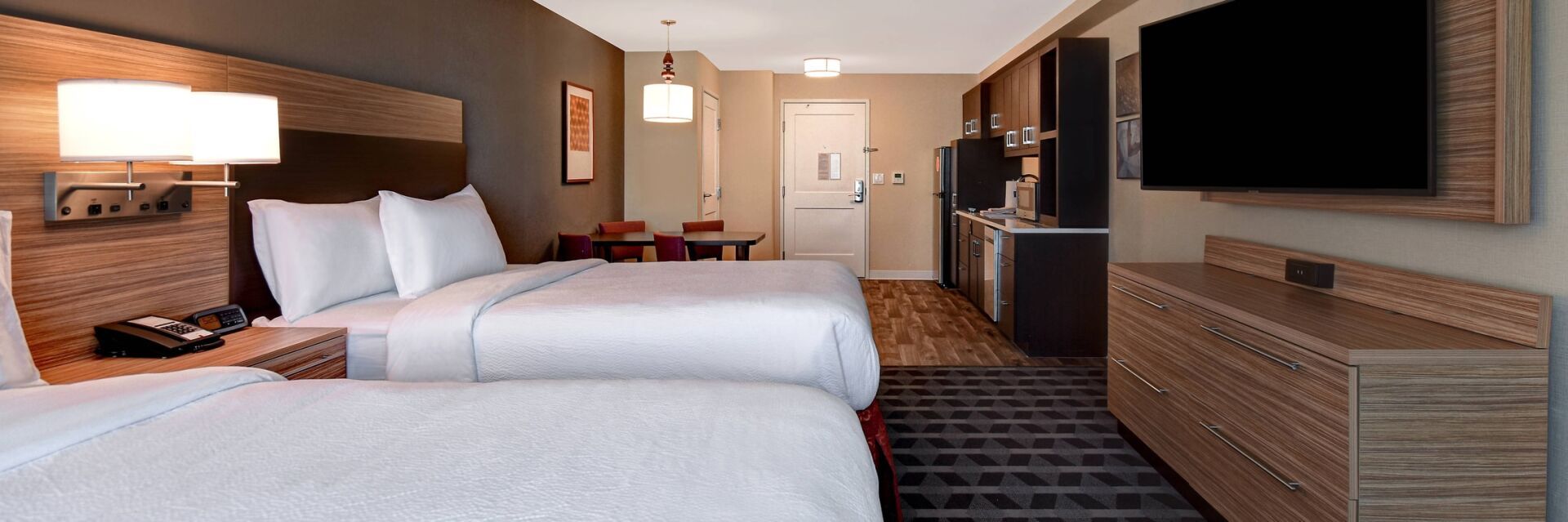 view to the two white hotel beds with a television and decorative lamps