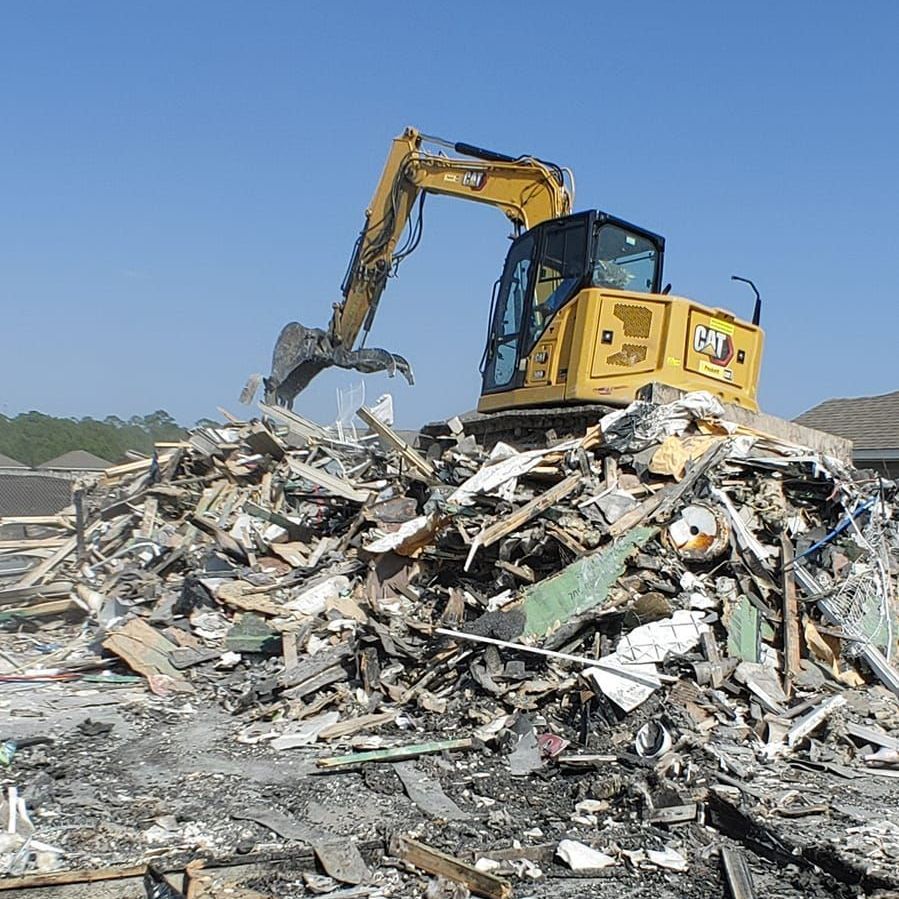 A cat excavator is working on a pile of rubble