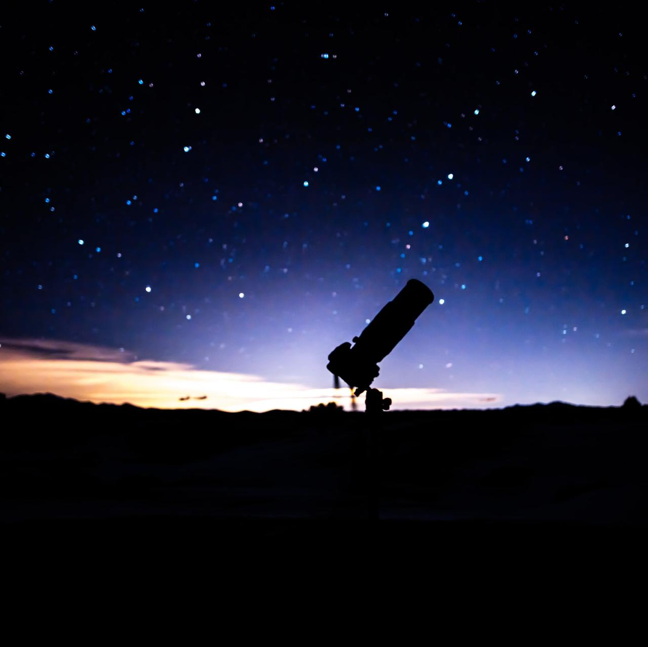 Photograph of a telescope in shadow against the night sky