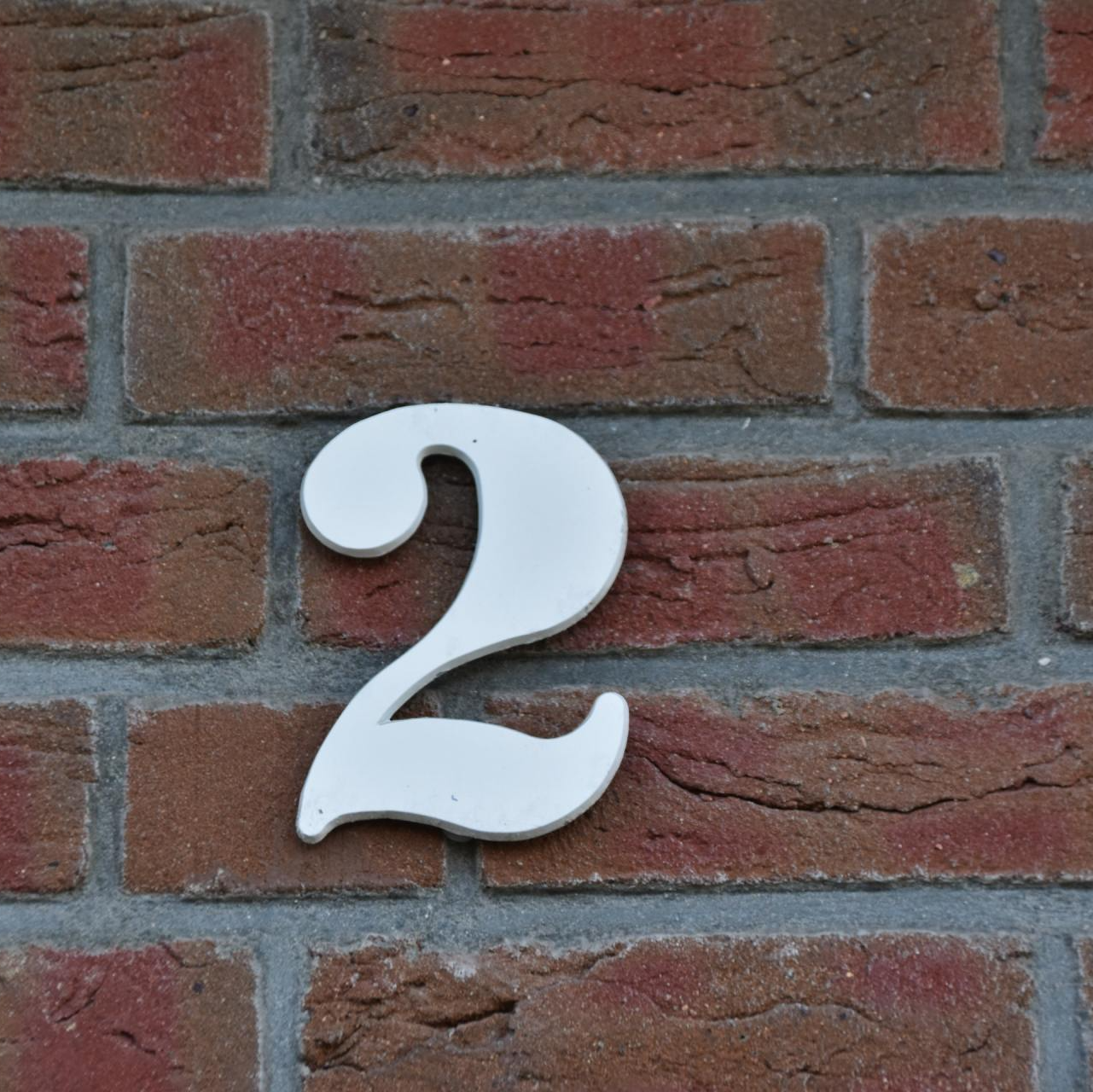 Photograph of a white number 2 against brick wall