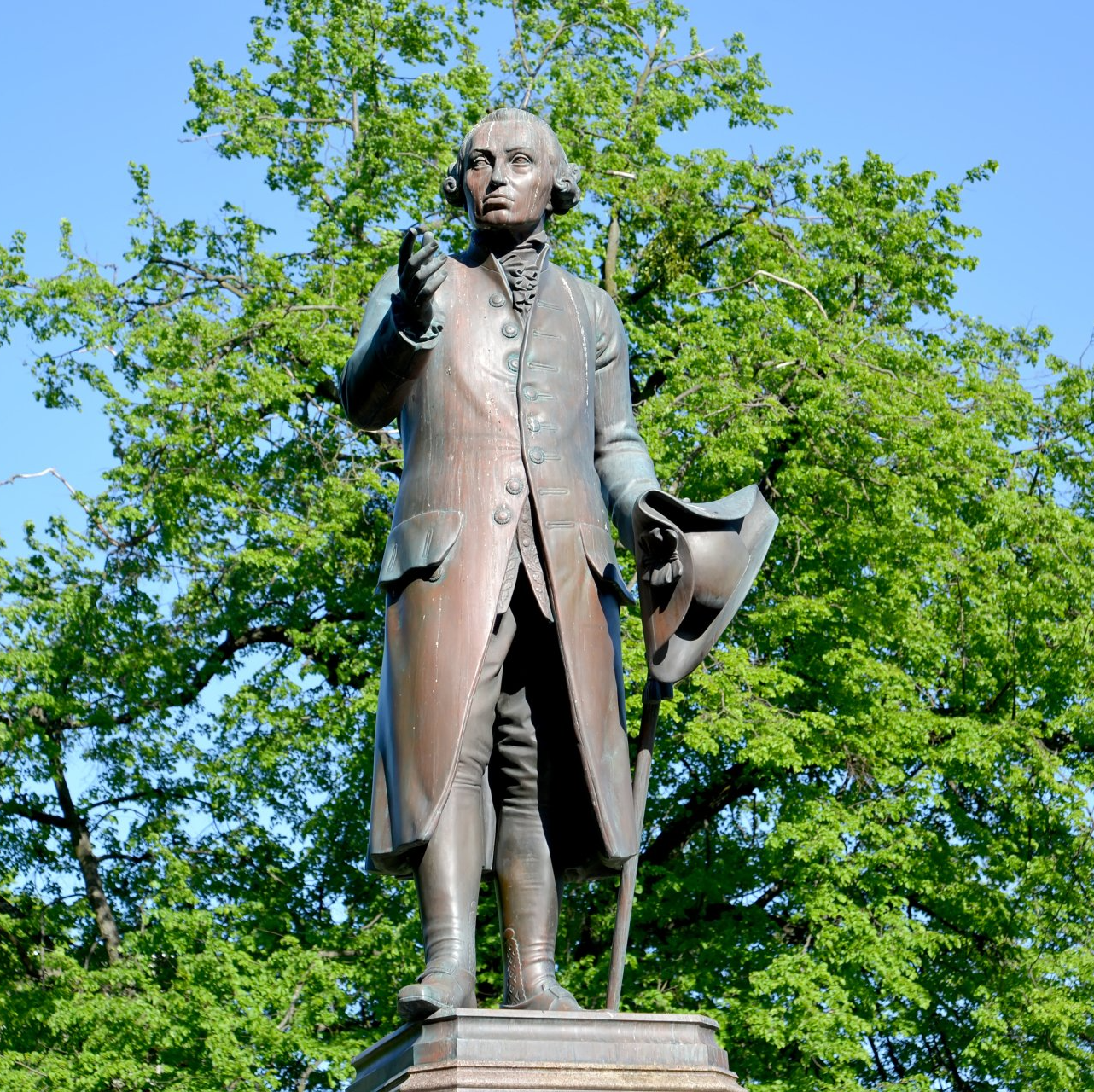 Stature of Immanuel Kant against green tree