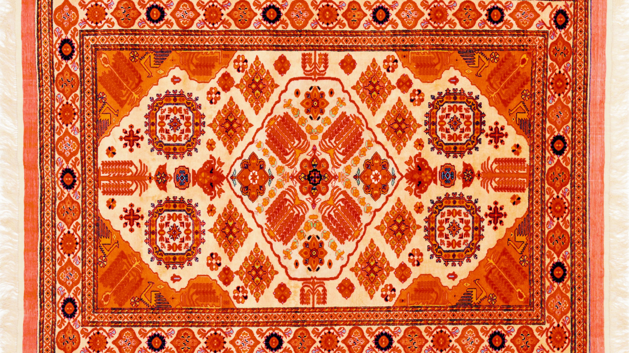 Orange and cream-colored rectangular rug with central medallion pattern and decorative border.