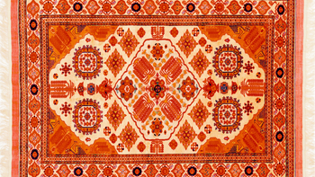 Orange and cream-colored Oriental rug with intricate geometric and floral patterns.