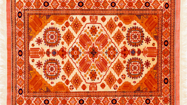 Orange and cream-colored Oriental rug with intricate geometric and floral patterns.