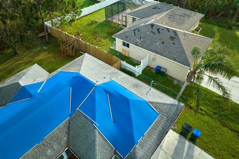 An aerial view of a house with blue cover on the roof