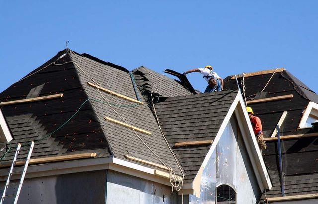 Two men are working on the roof of a house