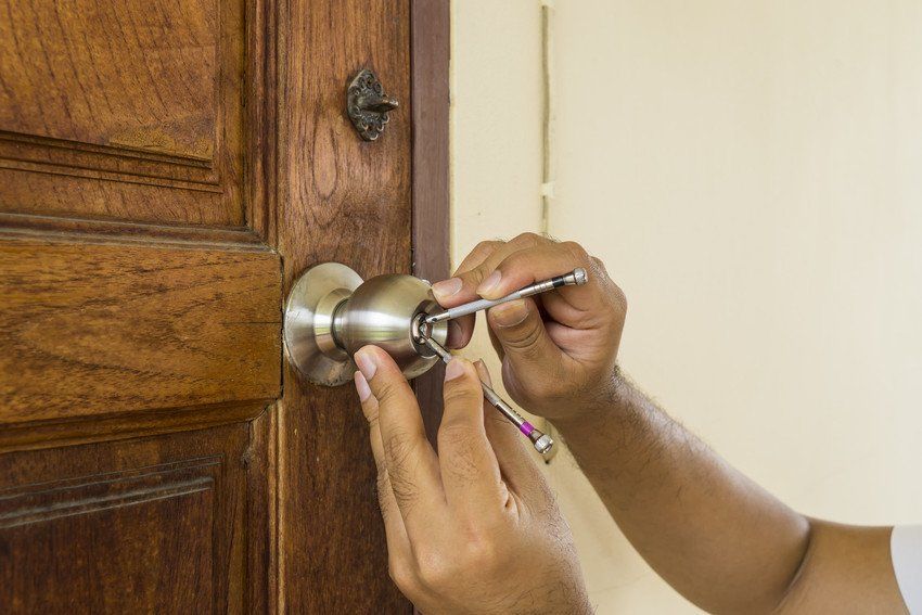 locksmith using lockpick tools to open wood door in emergency time