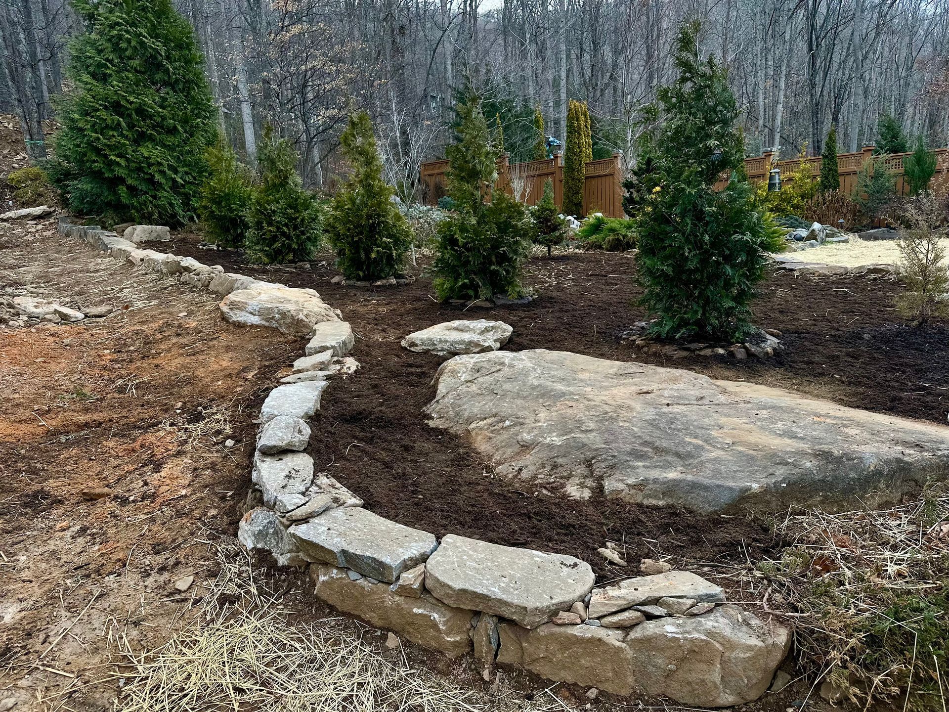 A stone wall is surrounded by trees and rocks in a garden.