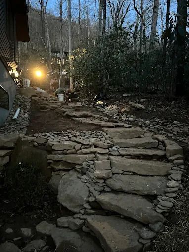 Stone steps leading up a hillside to a building, lit by a single bright light.