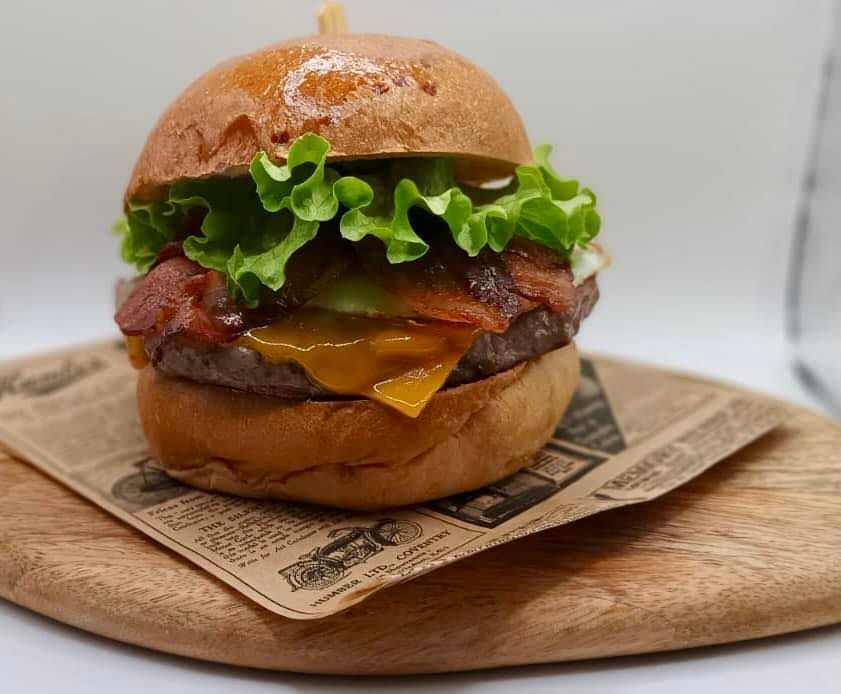 Un hamburger con lattuga e bacon su un tagliere di legno