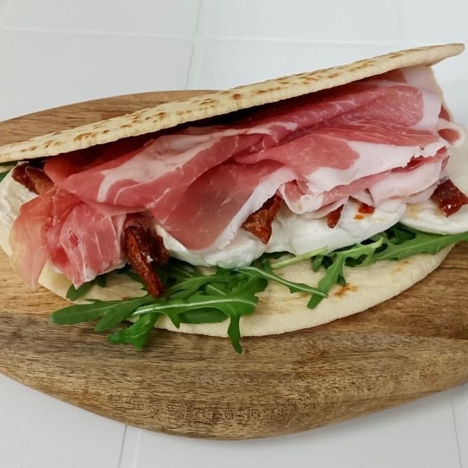 Un panino con carne e formaggio su un tagliere di legno