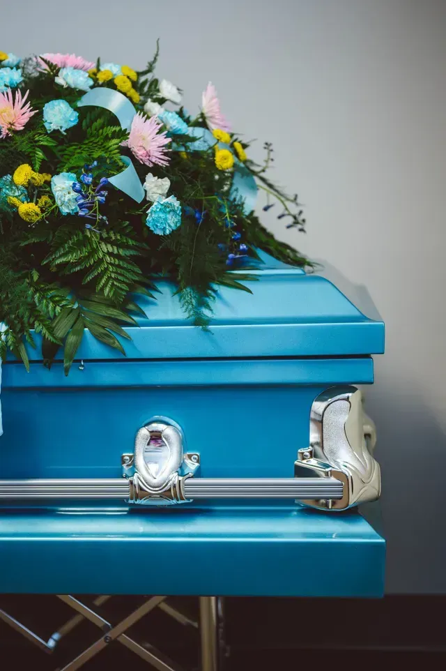 a blue coffin with flowers on it is sitting on a table .