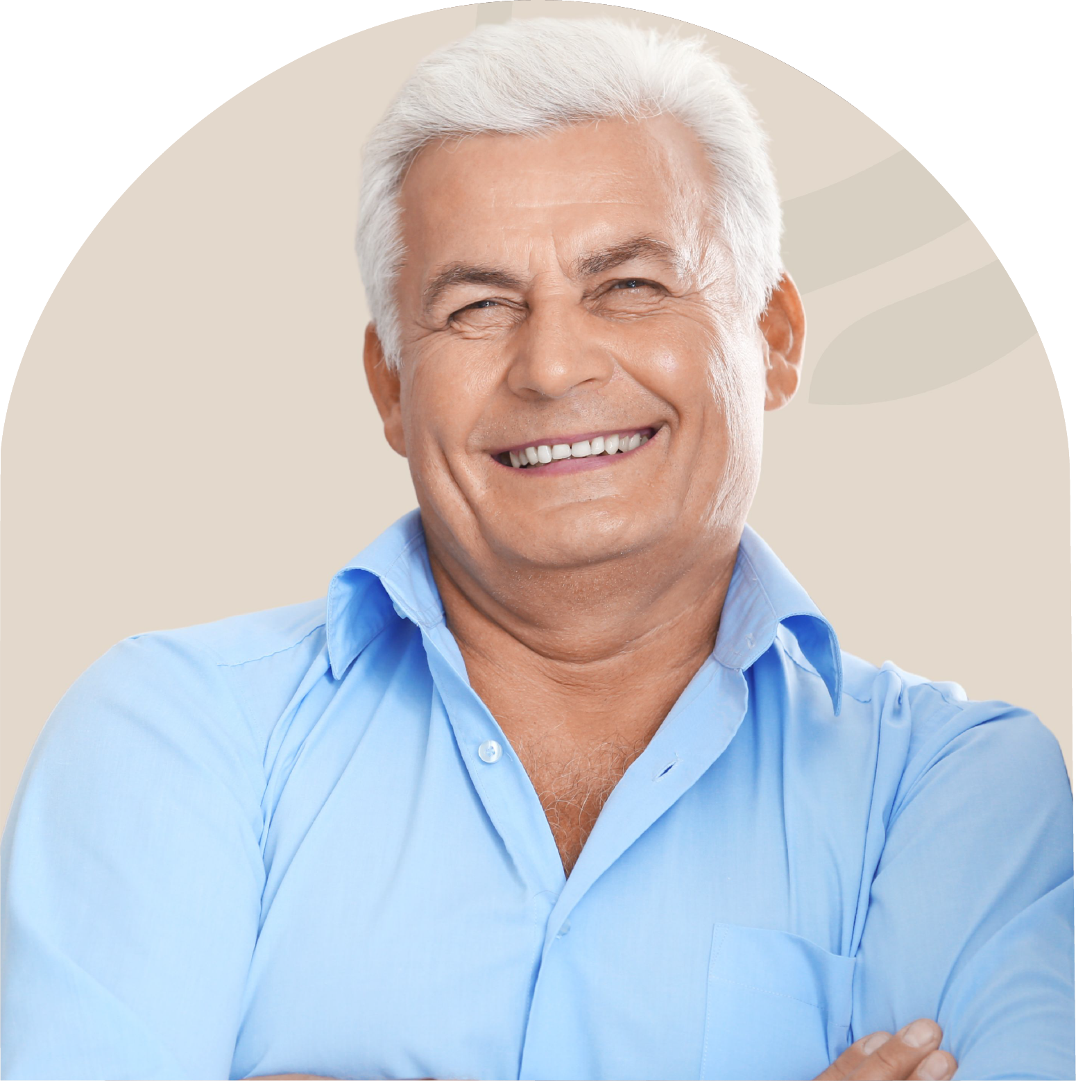 A man in a blue shirt is smiling with his arms crossed.