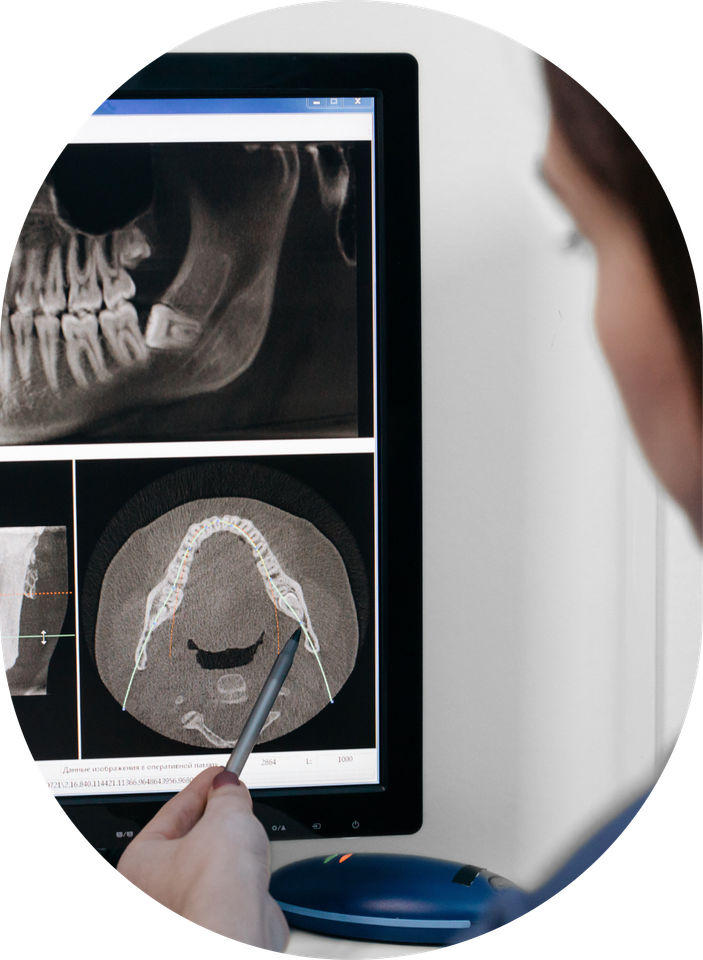 A dentist is looking at an x-ray of a person 's teeth on a computer screen.