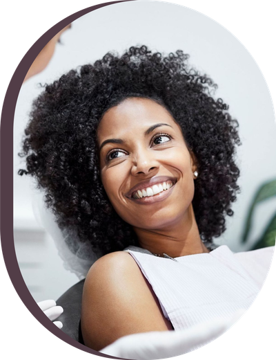 A woman with curly hair is smiling while sitting in a dental chair