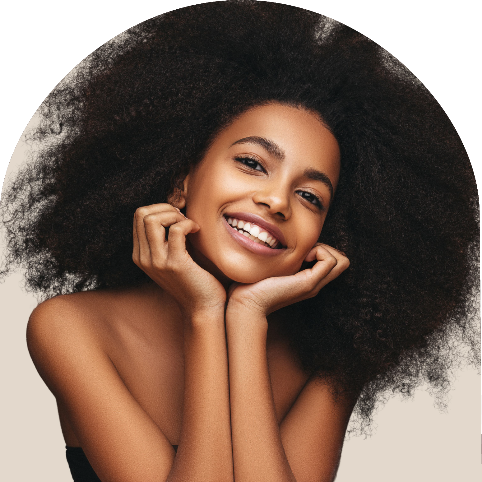 A woman with a large afro is smiling with her hands on her face.