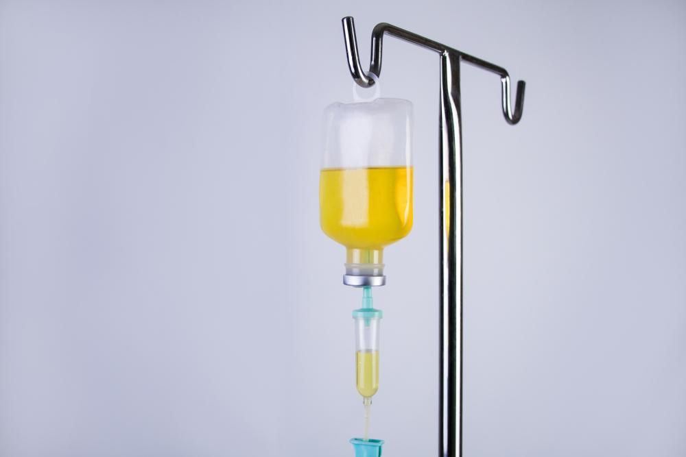 IV drip bag with yellow liquid, hanging from a metal pole.