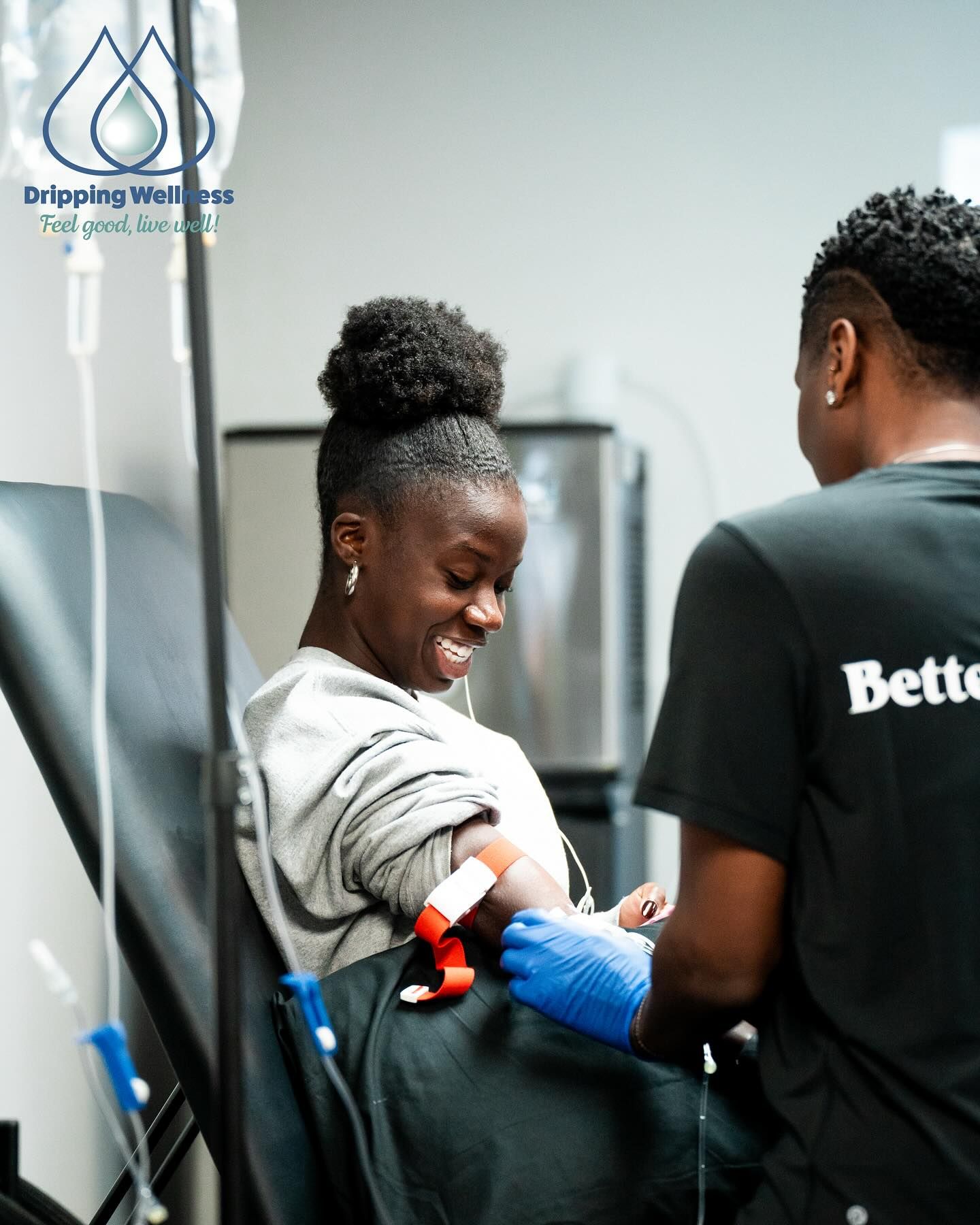 Person receiving intravenous therapy; medical professional prepares arm, smiling. 