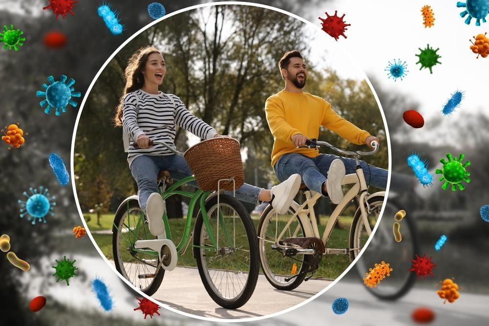 Two people on bikes surrounded by virus graphics, biking in park.