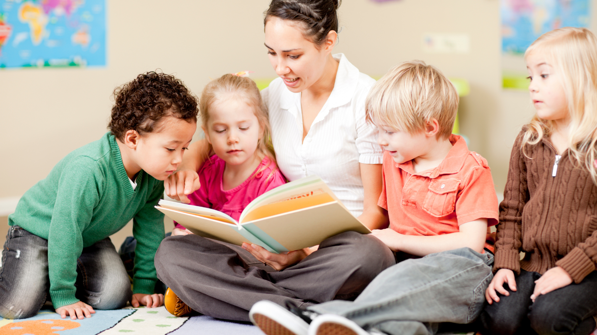 A woman is reading a book to a group of children.