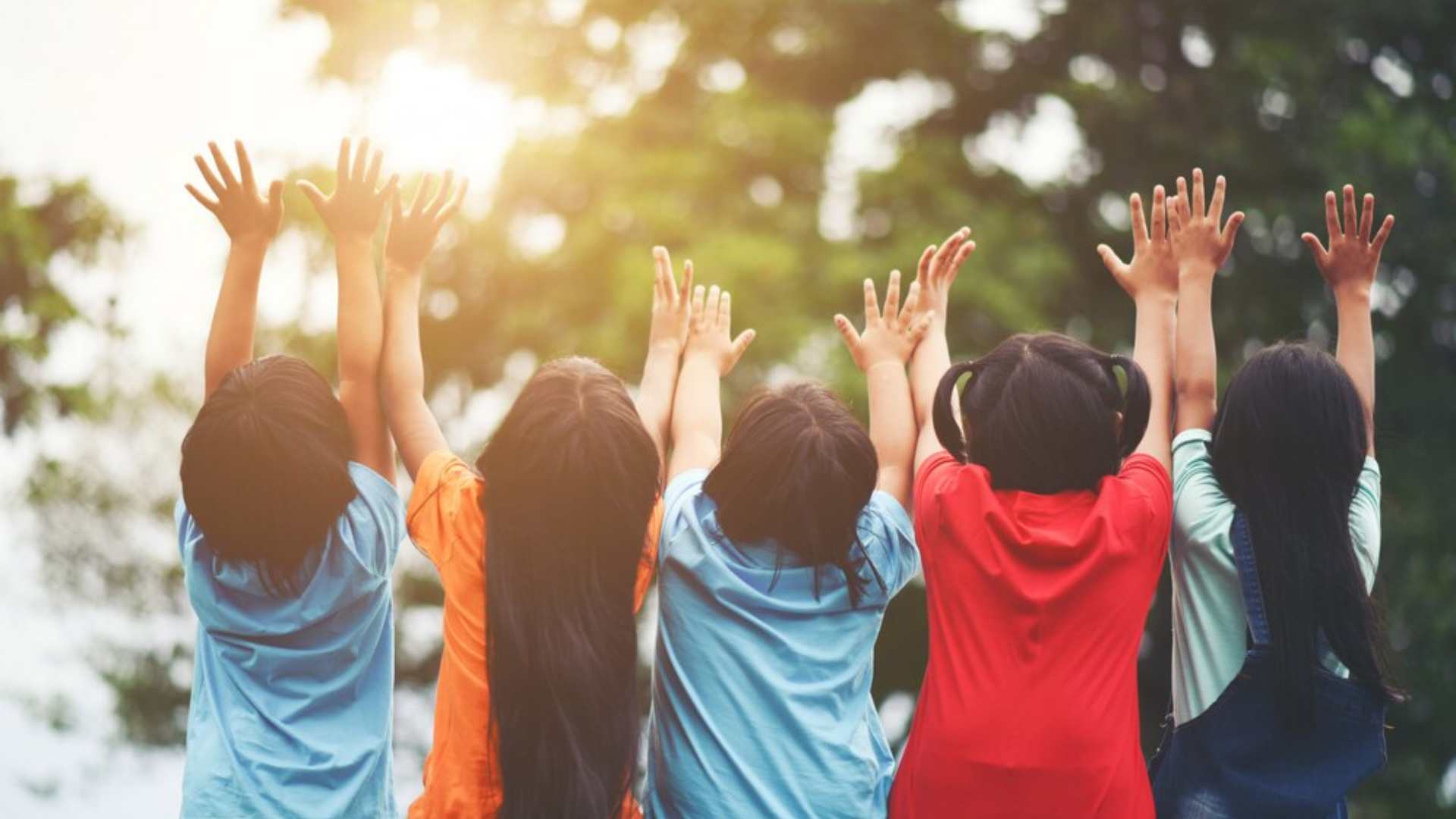 A group of children are raising their hands in the air.