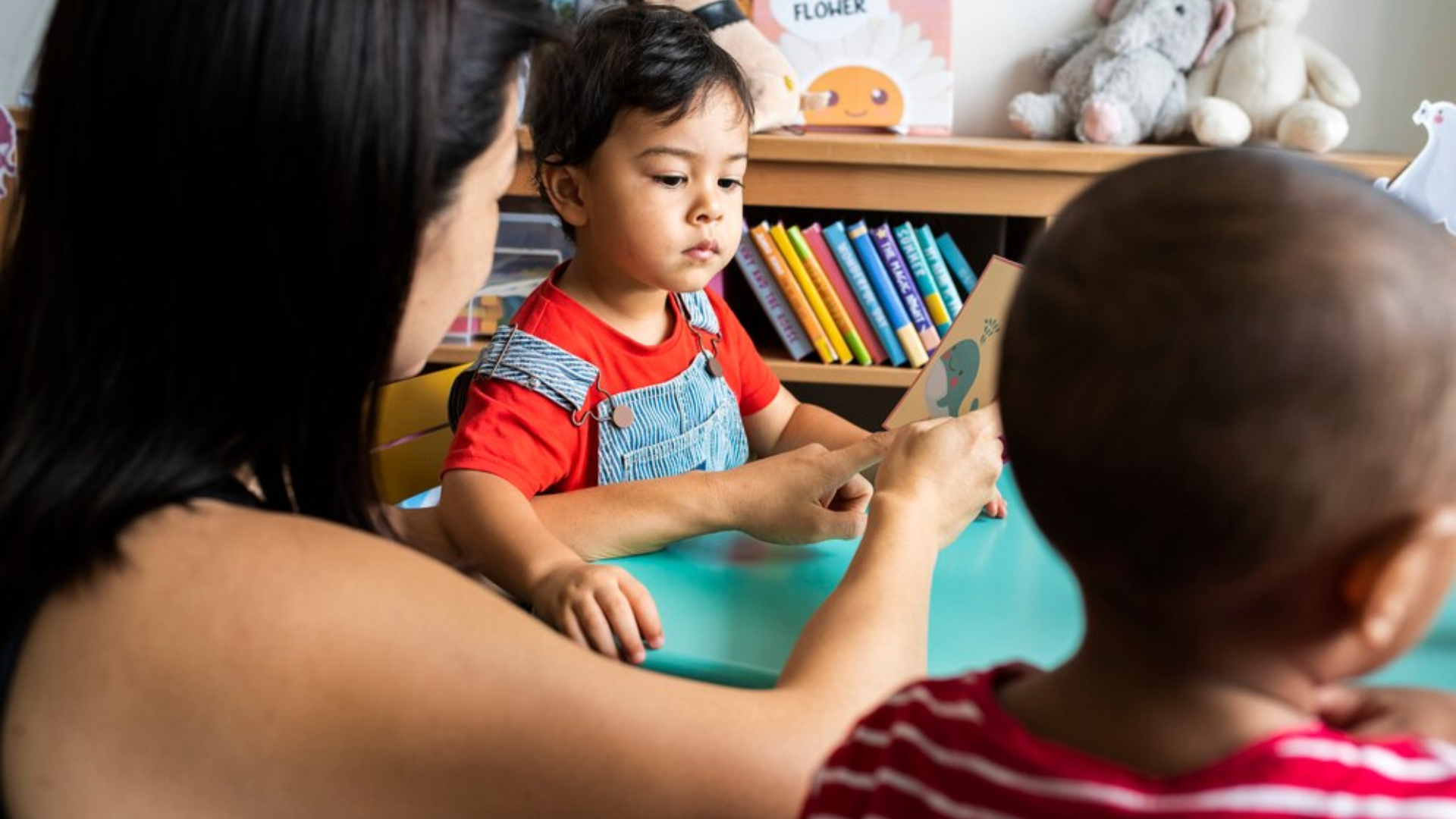A woman is sitting at a table with two children.