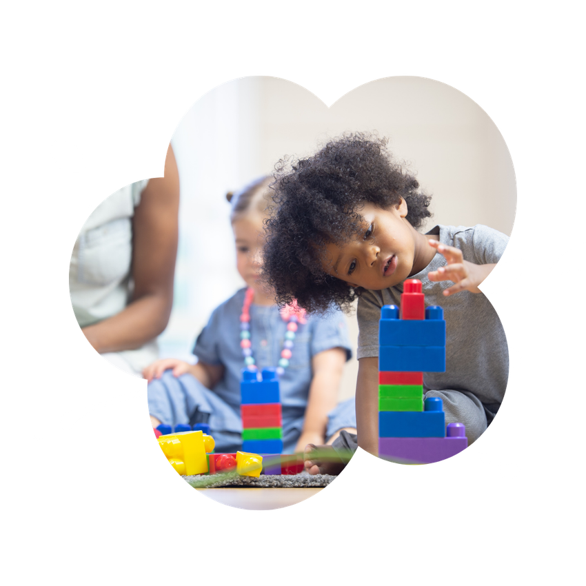 A boy and a girl are playing with blocks on the floor.