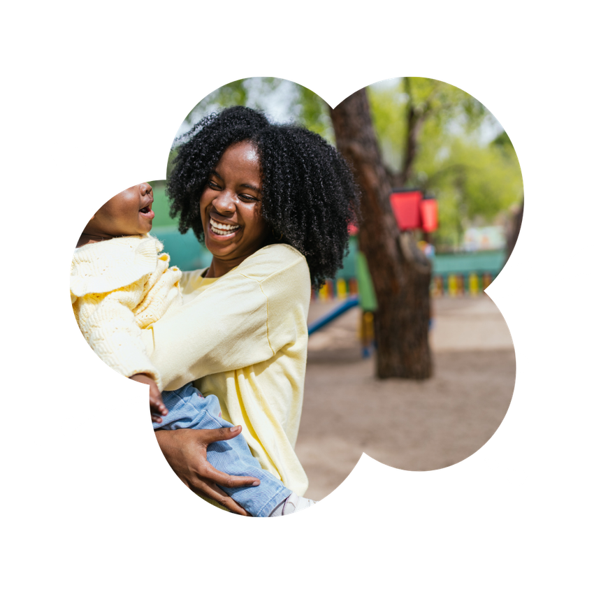 A woman is holding a baby in her arms in a park.