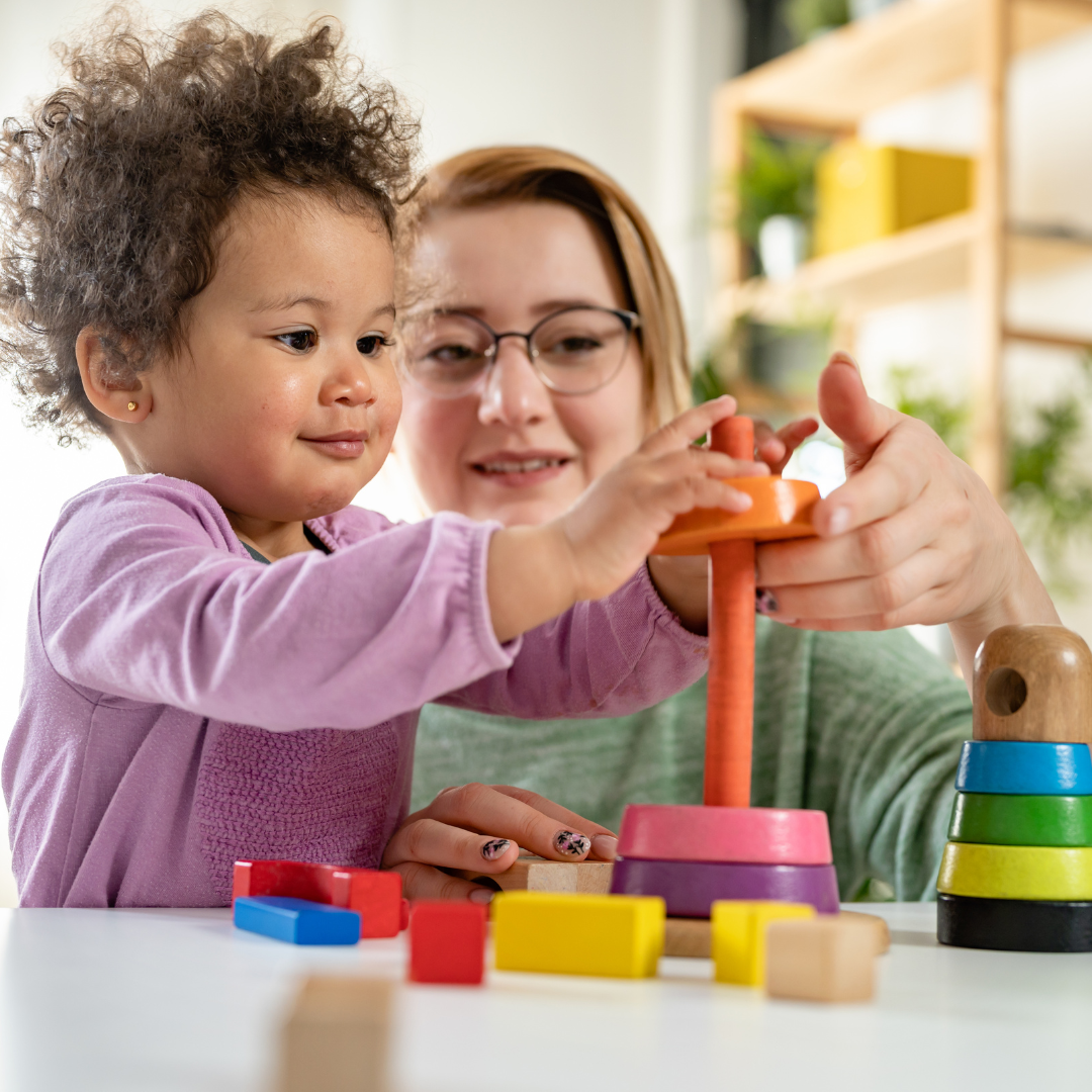 A woman and a little girl are playing with toys at a table.