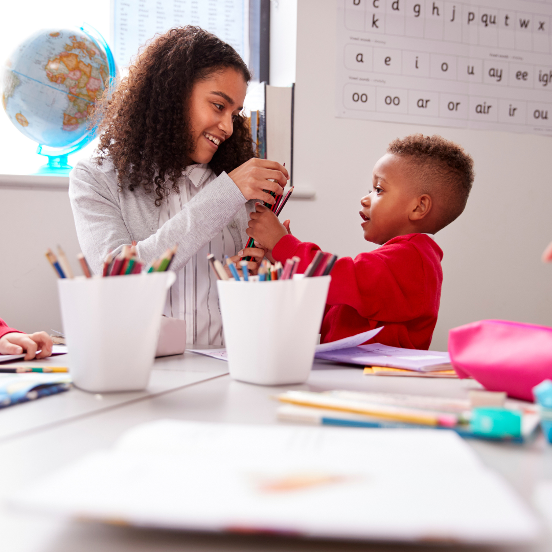 A woman and child are sitting at a table with pencils and a globe in the background.