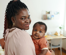 A woman is holding a baby in her arms.