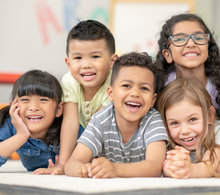 A group of children are posing for a picture together in a classroom.