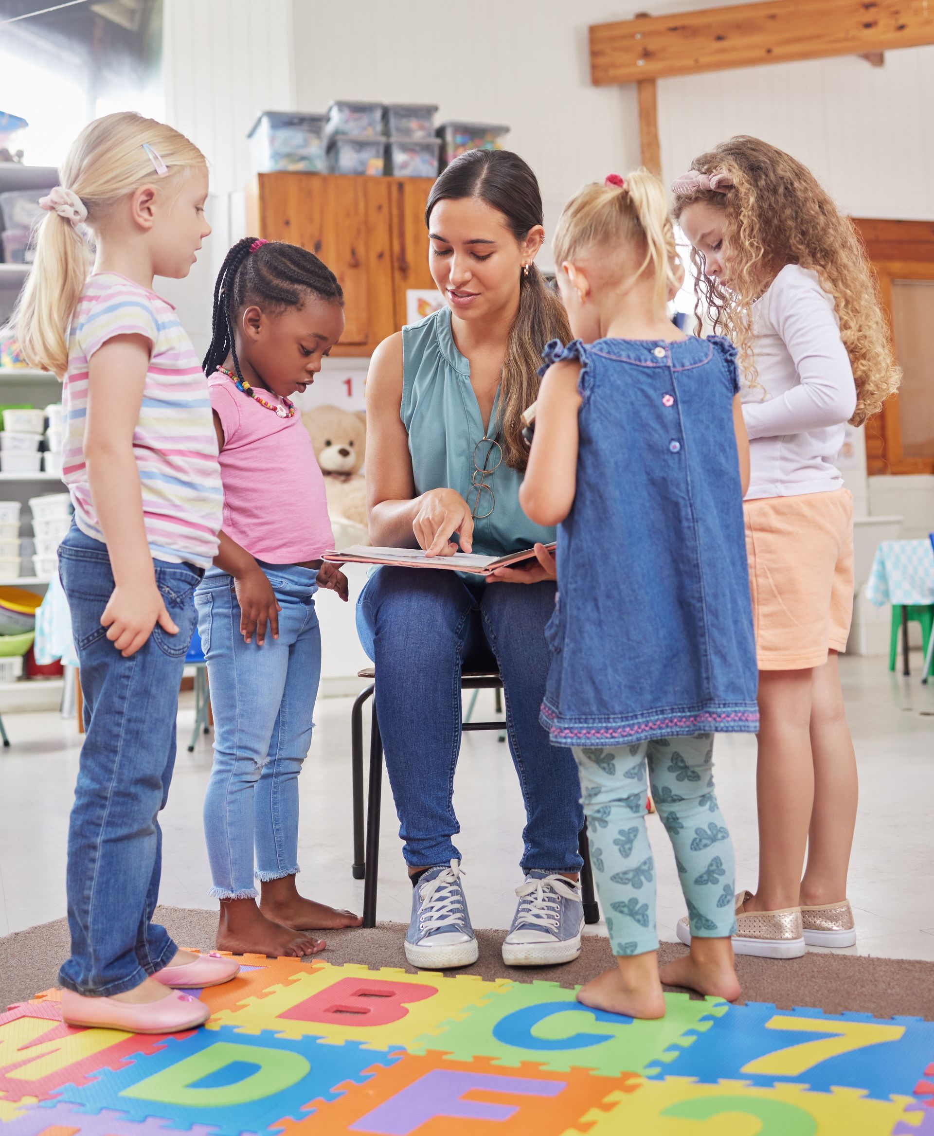 A teacher is teaching a group of young girls in a classroom.