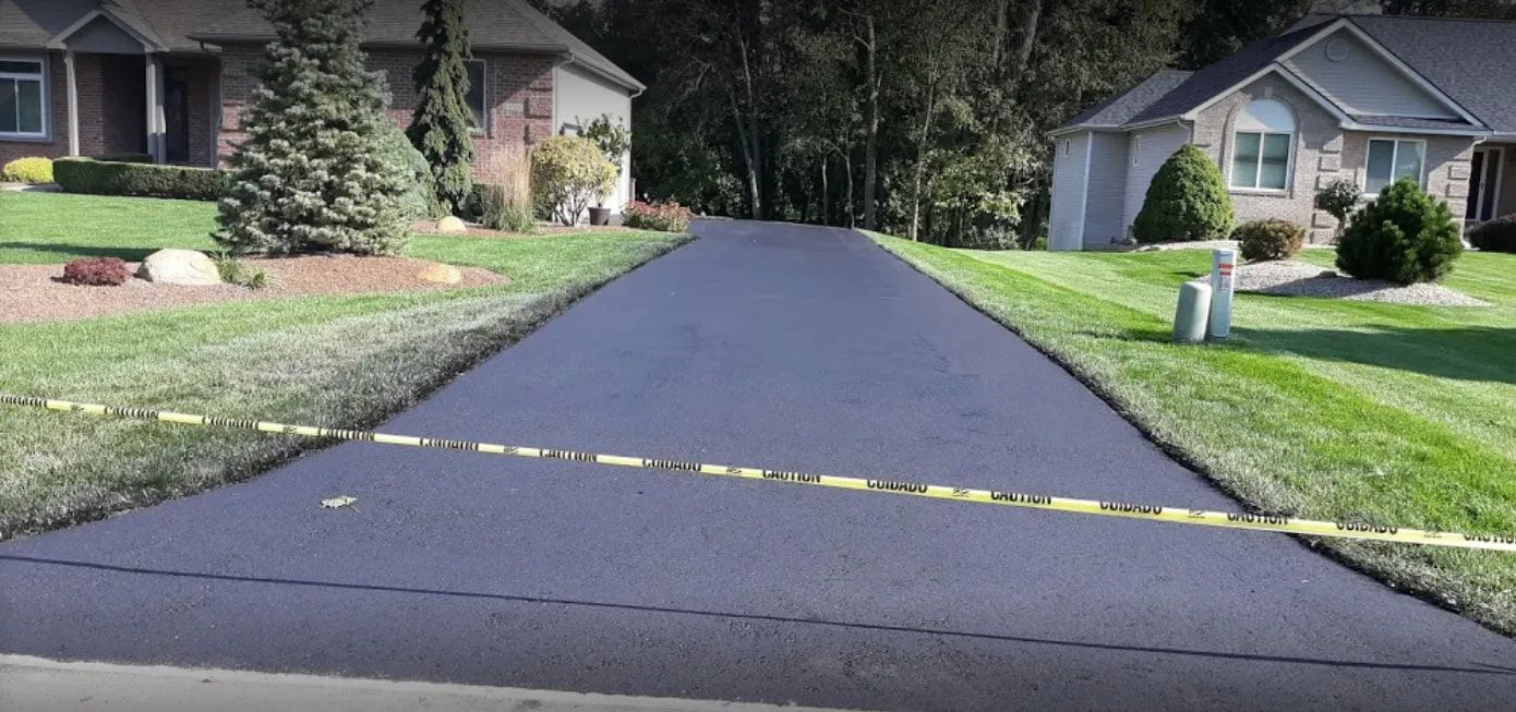 A newly paved driveway leading to a house in a residential neighborhood.
