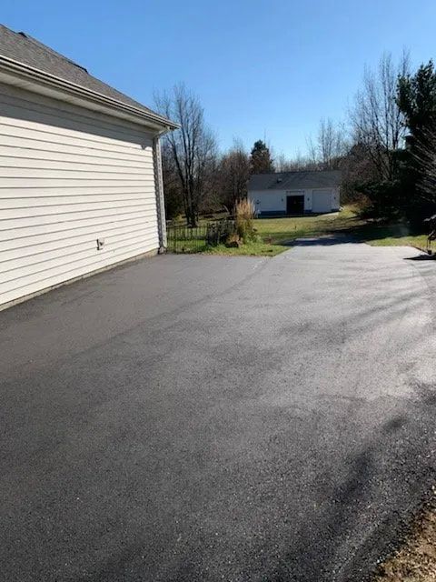 A driveway leading to a garage with a house in the background.