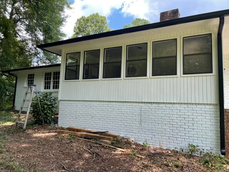 White house exterior with painted white brick base, black trim, and large windows.