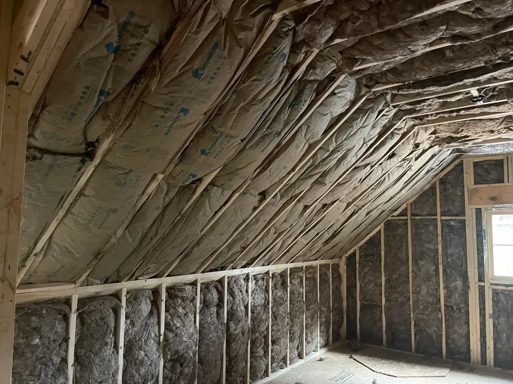 Interior of a room under construction, walls and angled ceiling filled with insulation.