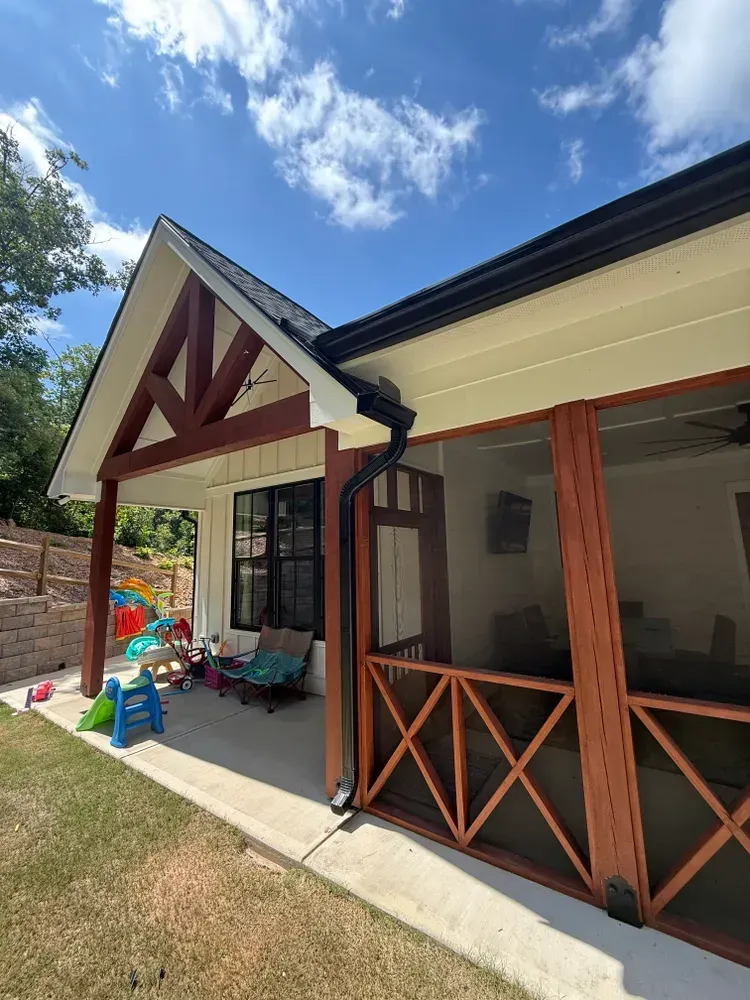 Exterior of a house with a screened porch and children's toys on the lawn.