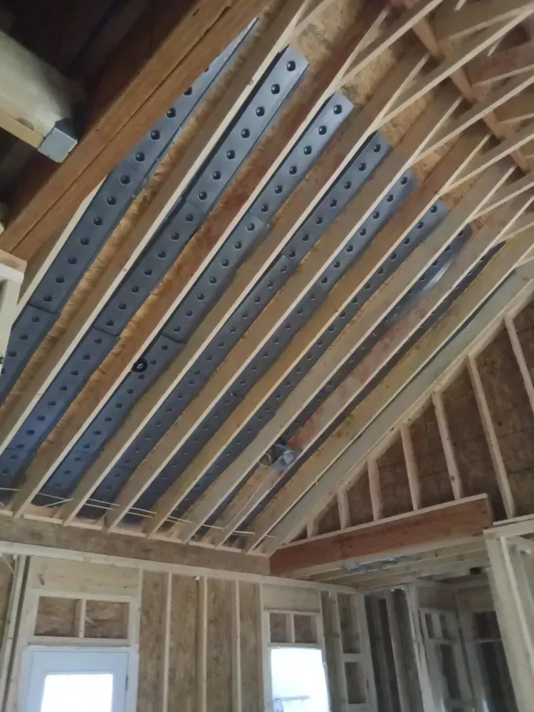 Wooden roof trusses with metal reinforcement plates in a building under construction.