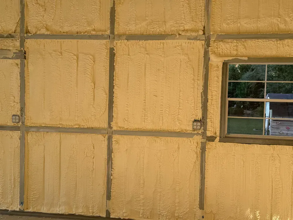 Foam insulation on interior wall of building; window and electrical outlets visible.