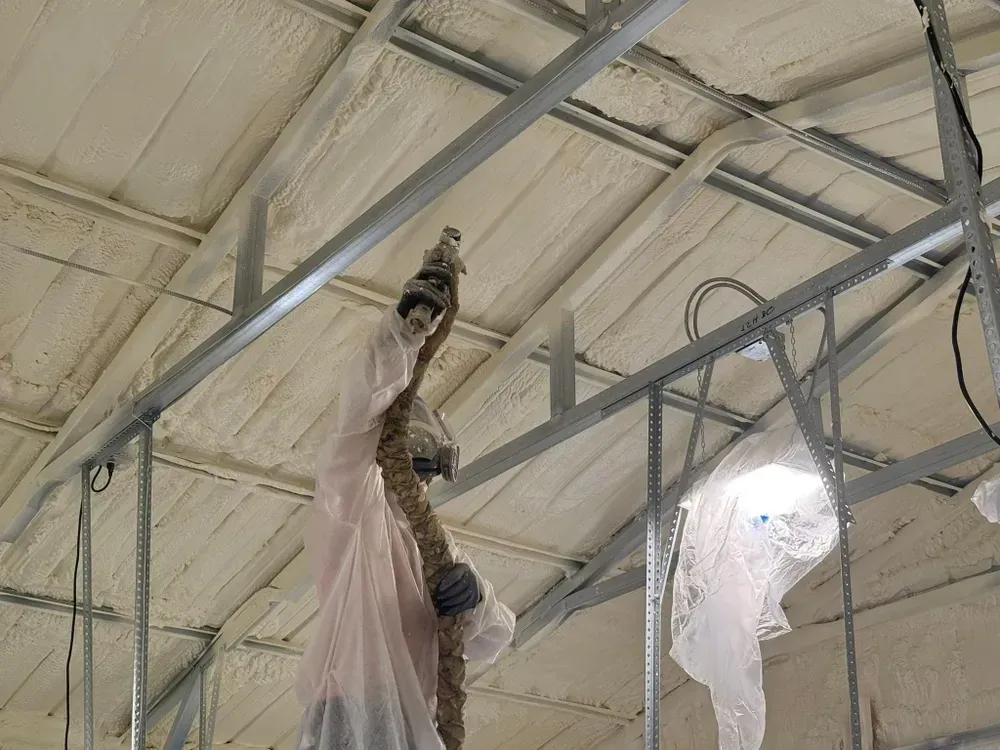 Interior view of a building under construction, spray foam insulation on ceiling, metal beams.