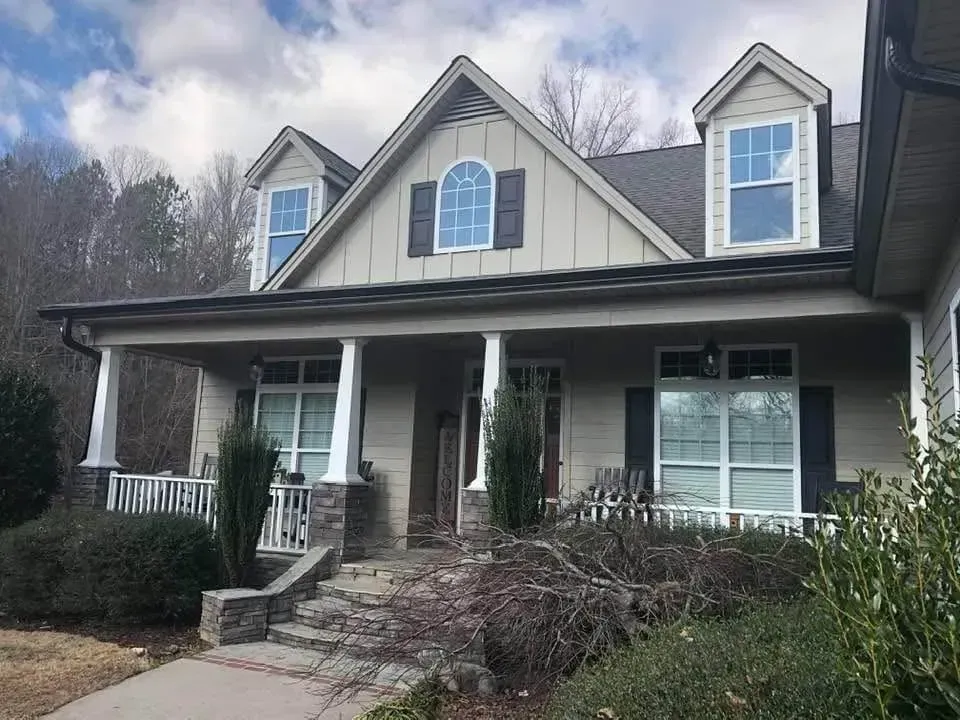 Tan and gray house with a porch, stone steps, and two dormers.