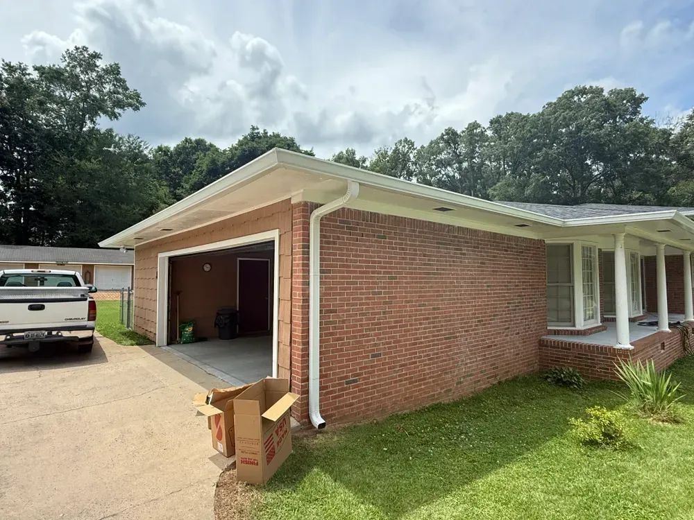 Brick house with an open garage, white trim, and a truck parked outside.