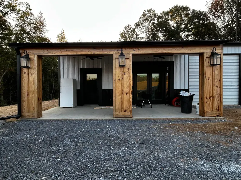Garage with wooden supports, corrugated metal siding, and stone driveway.