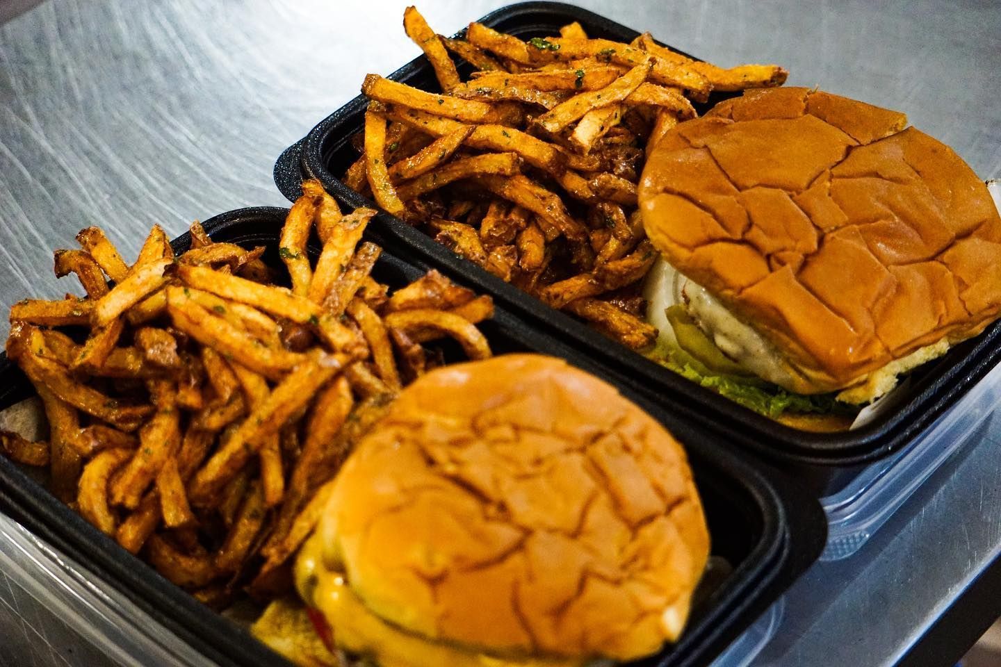 A hamburger and french fries in plastic containers on a table.