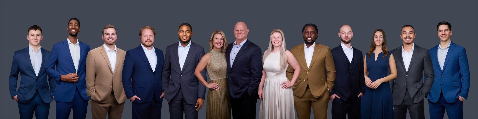 A group of people in suits and dresses are standing in a row.