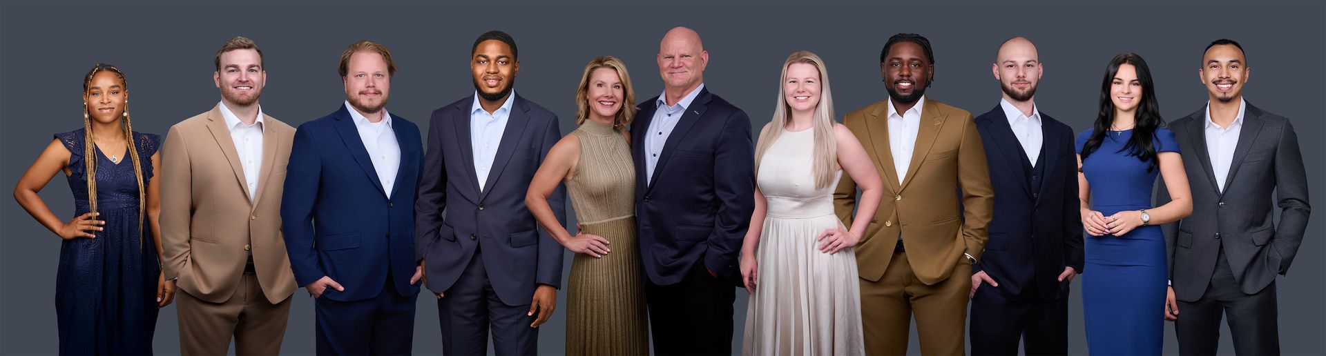 A group of people in suits and dresses are standing in a row.