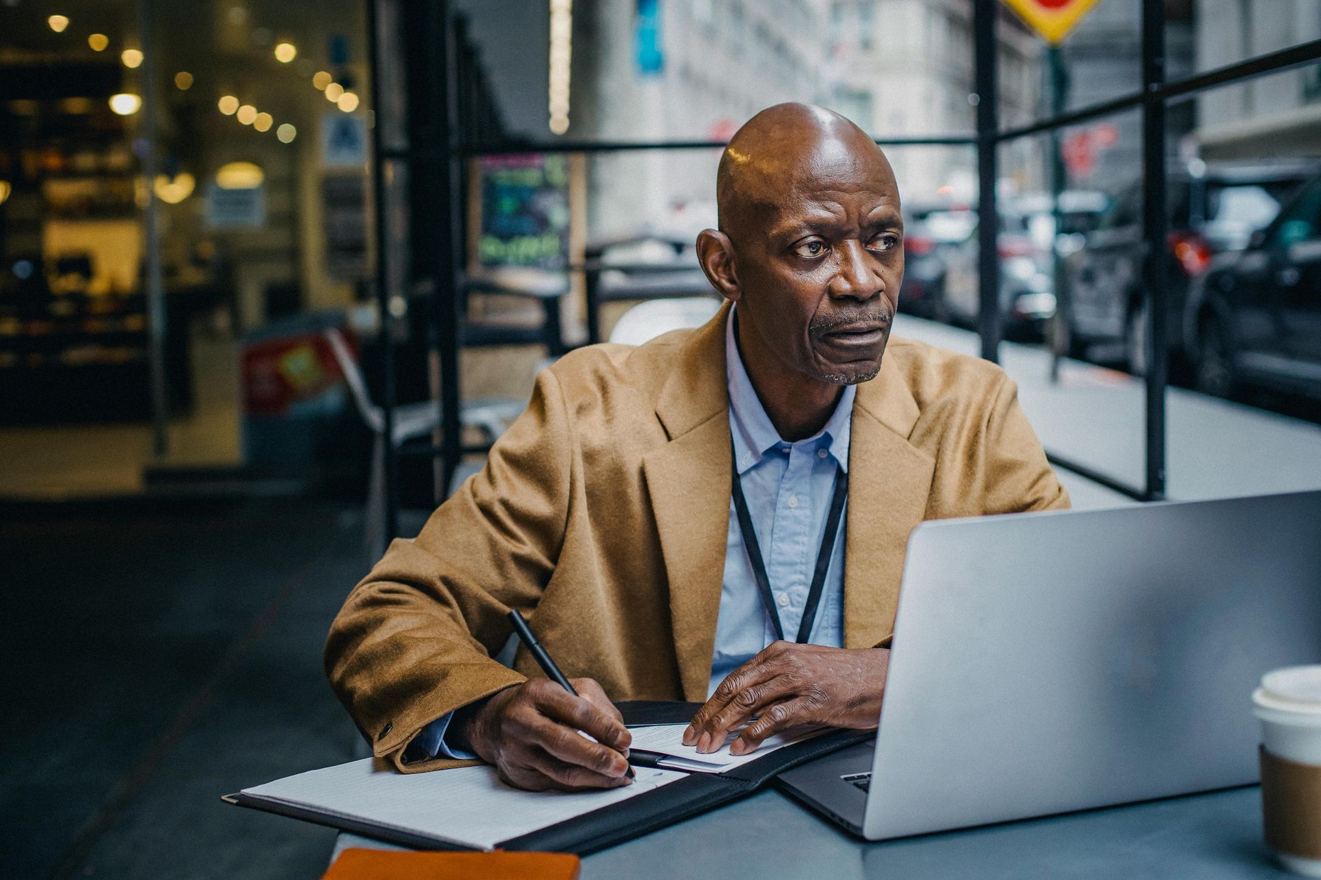 A man is sitting at a table with a laptop and a notebook.