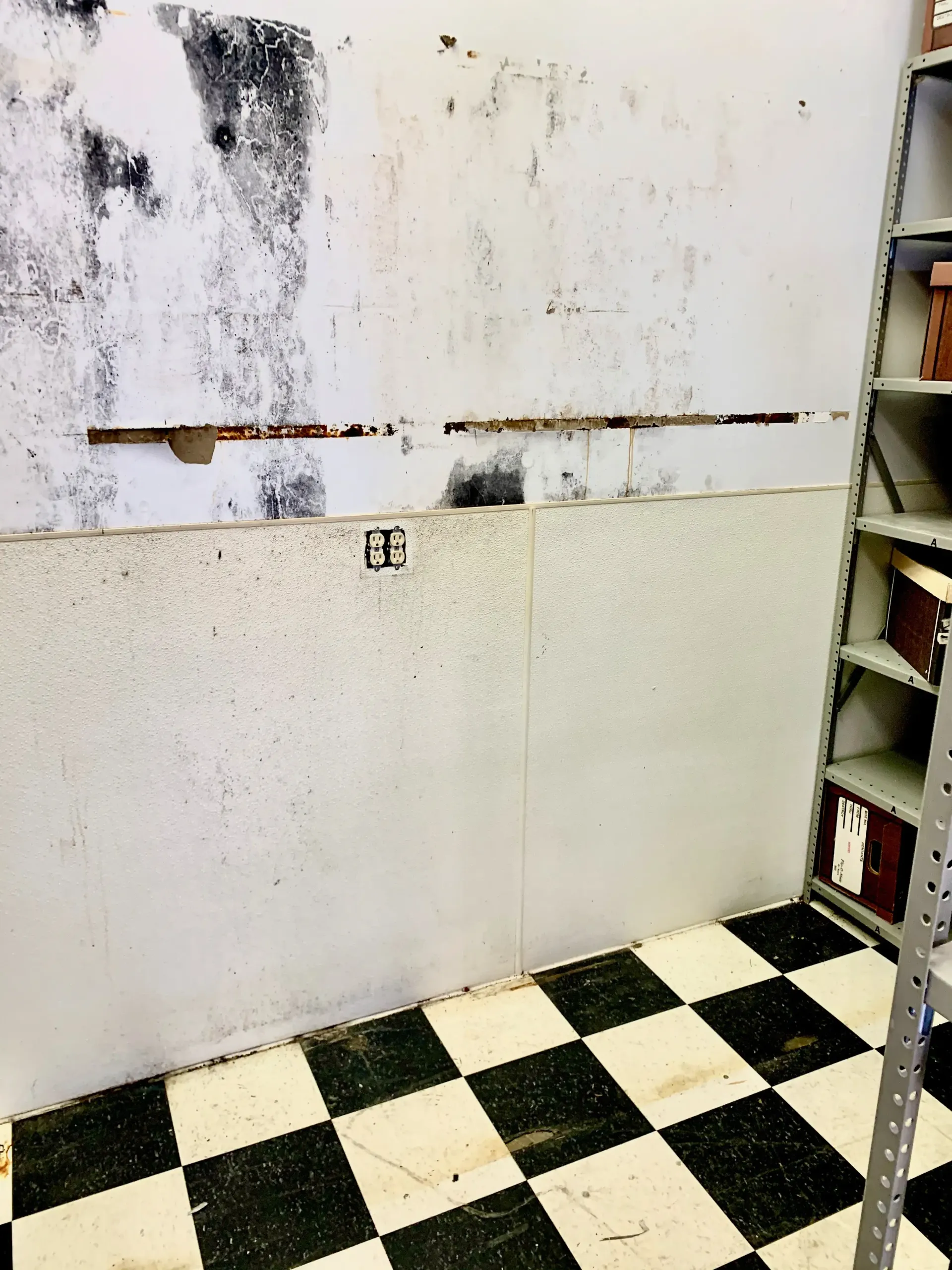 A room with a checkered floor and a white wall.