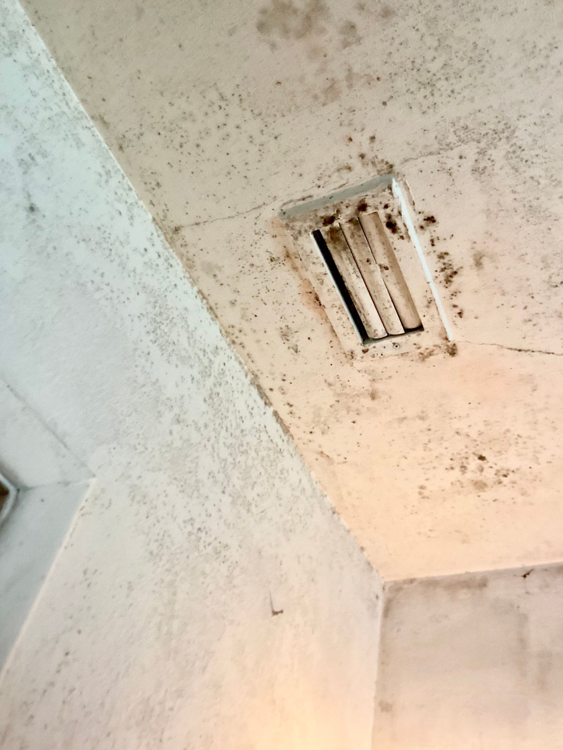 A dirty ceiling with a vent on it.